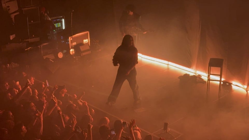 070 Shake performing on stage. She is backlit with orange lighting.
