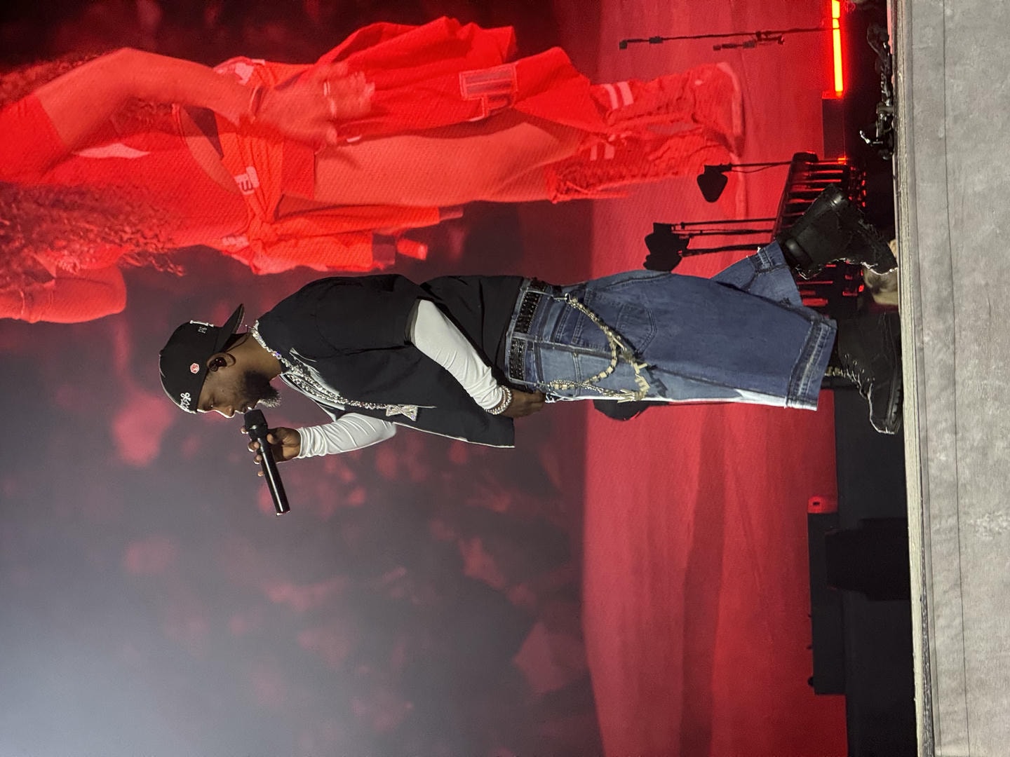 Kendrick Lamar performing on stage. He has the mic lifted up to his mouth.