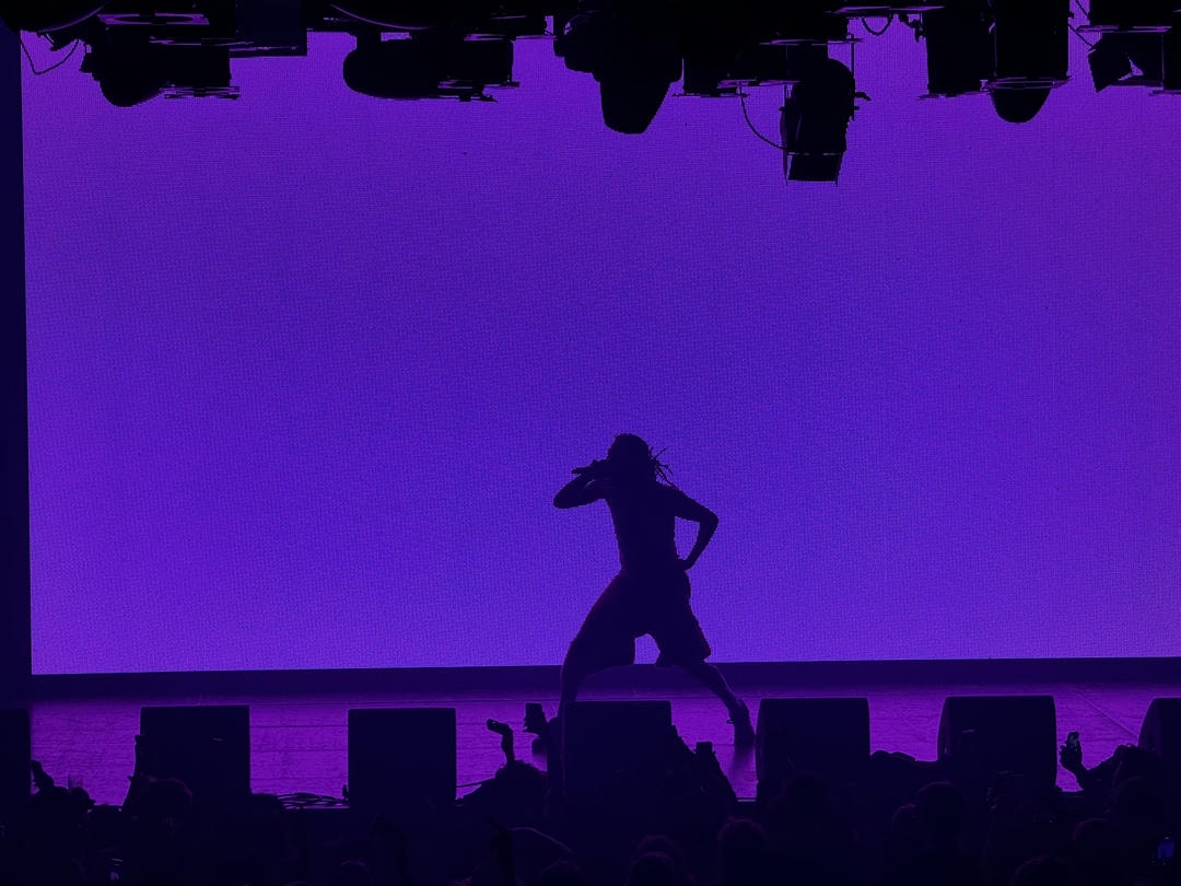 Aminé's silhouette backlit by a purple LED screen.