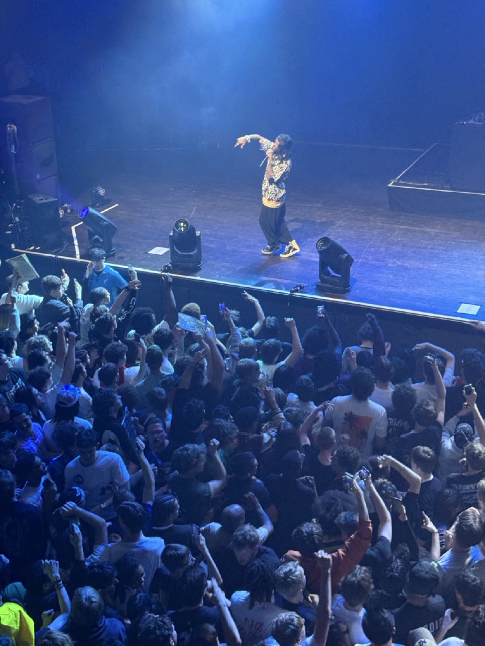 JID performing live on stage as seen from above.