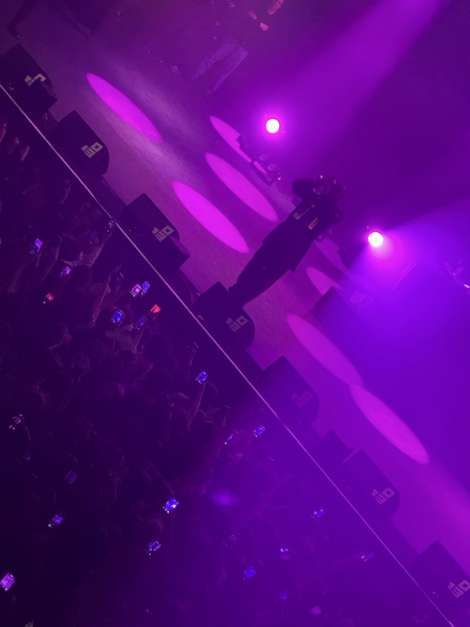 Freddie Gibbs rapping on stage. The background lighting is purple, and the bottom left half of the screen is filled with the audience.
