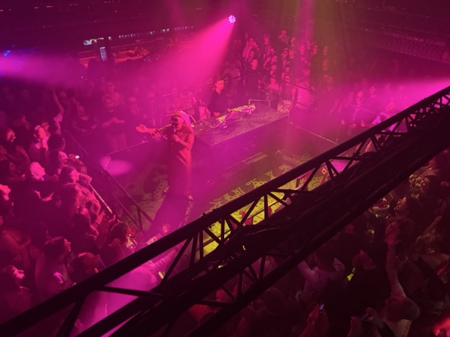 Omar Souleyman on stage, performing for a crowd that completely surrounds the square stage he and his DJ are on.