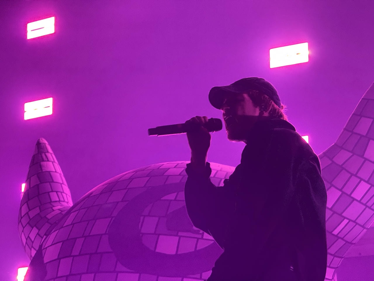 Joey Valence performing live on stage. He's backlit by indigo lights, causing him to be more of a silhouette.