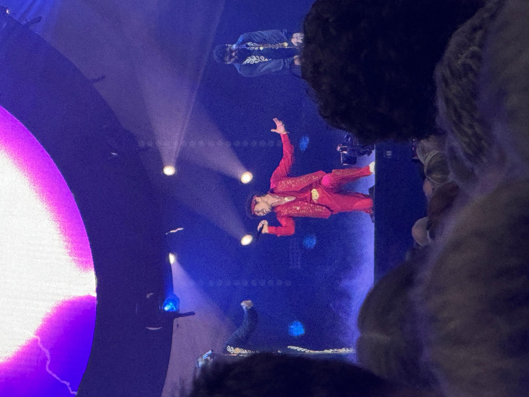 Bruno Mars kneeling down on stage singing into his microphone.