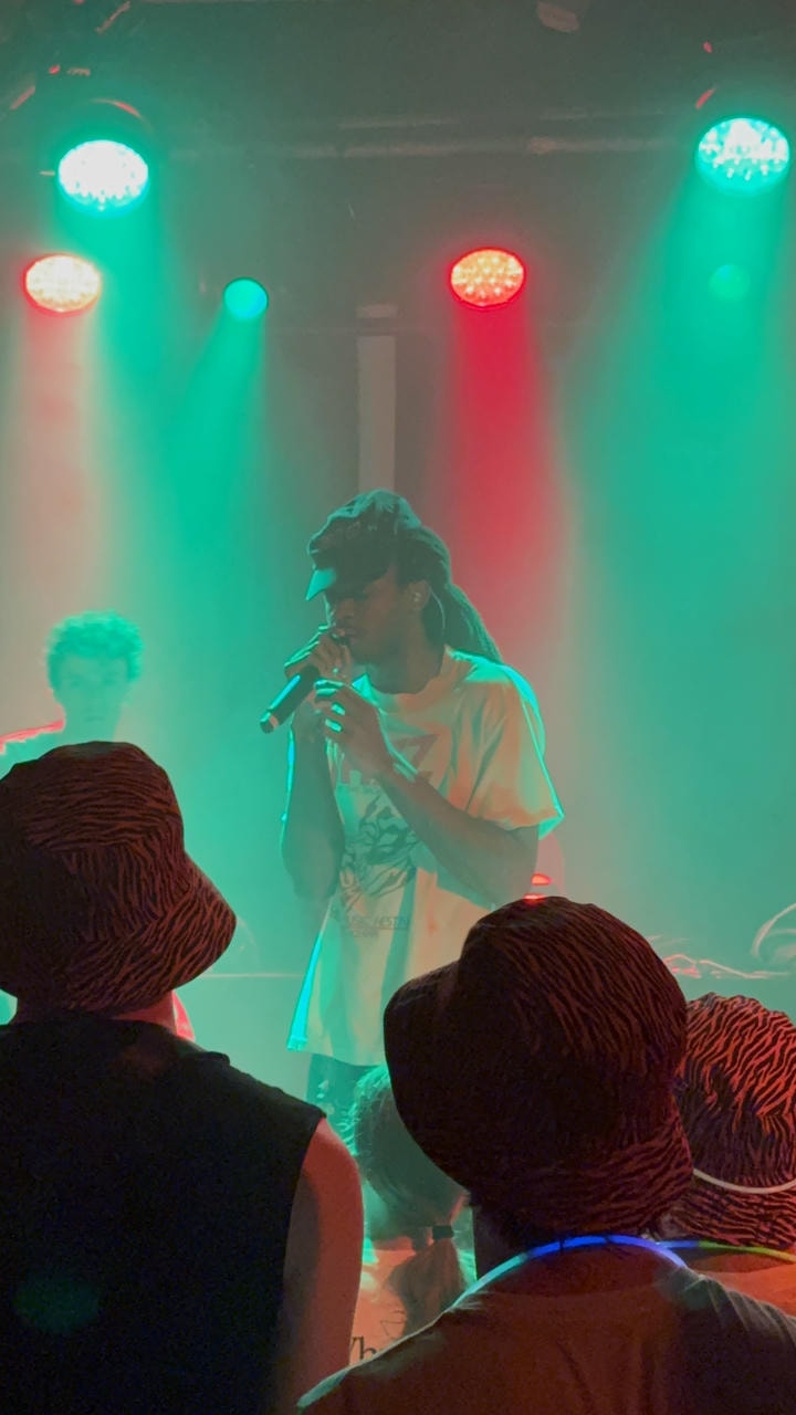 Cisco Swank of WHATMORE singing into the microphone on stage.