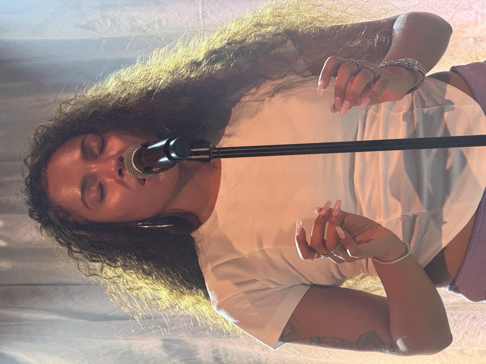 Samara Cyn with her eyes singing into the microphone in a stand.